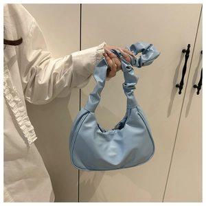 Detail of light blue pleated cloud handbag with soft ruched handle and PU leather texture