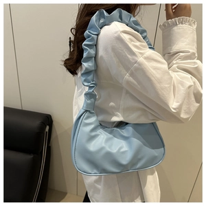 Side view of light blue pleated shoulder bag made of premium PU leather on a model