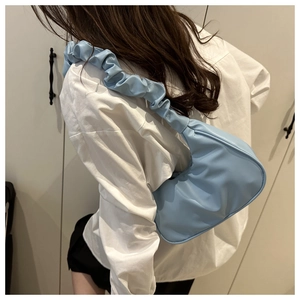 Detailed view of light blue pleated shoulder strap bag worn by model in casual setting