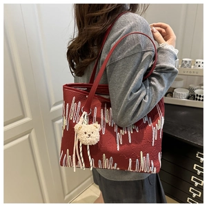 Detail der roten geprägten Tragetasche mit Bärenanhänger an einem Schultermodell