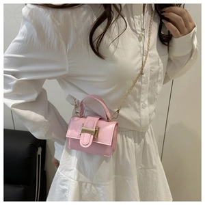 Close-up of pink mini crossbody bag featuring a gold H-shaped buckle and metal chain