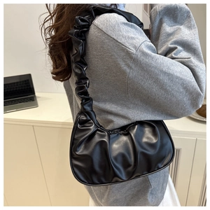 Detail of a black ruched cloud hobo bag with a pleated shoulder strap and matte leather finish