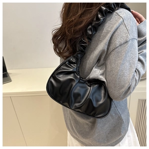 Minimalist black pleated cloud shoulder bag shown on model in a modern lifestyle setting