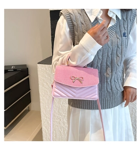 Detailed view of pink crossbody bag with V-shaped quilting and golden bow decoration