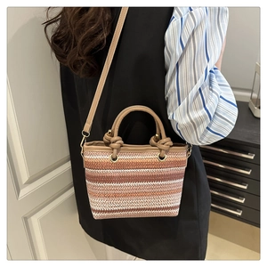 Detail of colorful striped woven beach bag with leather handles and adjustable shoulder strap