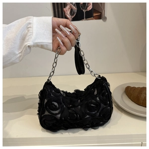 Detail of a black lace rose clutch bag featuring 3D mesh petals and a silver chain strap