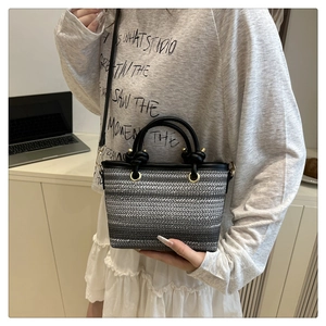 Détail du sac seau tissé à rayures avec poignées noires et anneaux dorés