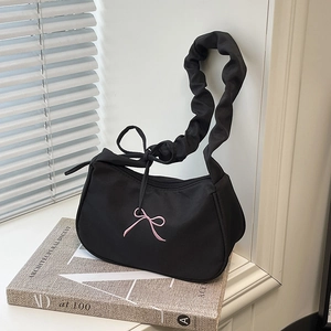 Chic black underarm bag with pink bow embroidery and ruffled strap on fashion book