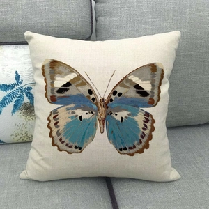 Detail view of square linen cushion featuring colorful butterfly pattern on grey sofa