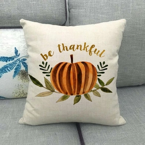 Linen autumn pumpkin pillow cover with be thankful gold lettering on a grey fabric sofa