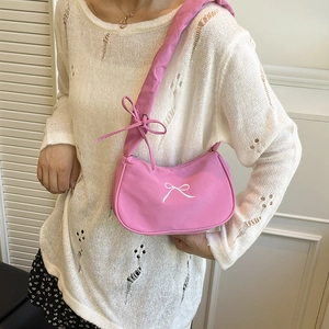 Pink crescent underarm bag with white bow pattern and wide strap on shoulder
