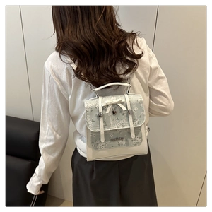 Close-up of blue floral backpack featuring white leather bow and heart metal pendant