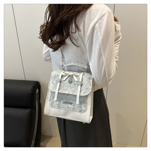 Detail of floral patchwork backpack with white leather bow and heart-shaped metal pendant