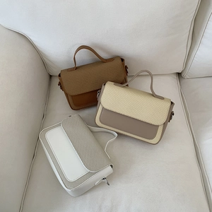 Drei minimalistische Umhängetaschen in Braun, Beige und Weiß mit gewebter Textur auf Sofa