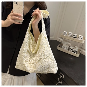 Gros plan détaillé sur la texture dentelle florale et les paillettes du sac cabas blanc
