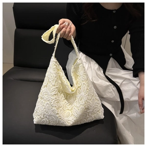 Détail d'un sac cabas en dentelle blanche avec motifs de papillons au crochet