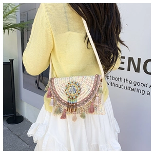 Close-up of bohemian woven crossbody bag with colorful embroidery and tassel detail