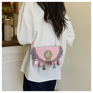 Detail of pink woven crossbody bag with colorful beaded embroidery and long fringe tassels