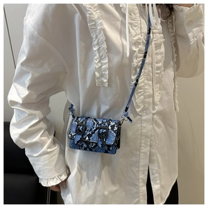 Dettaglio della mini borsa a tracolla blu motivo pitone con doppie fibbie decorative