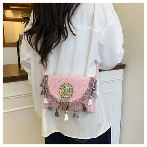 Dettaglio della borsa a tracolla intrecciata rosa con logo di perline e nappe a frange