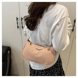Detail of peach pebbled leather shoulder bag with gold chain and red fruit charm