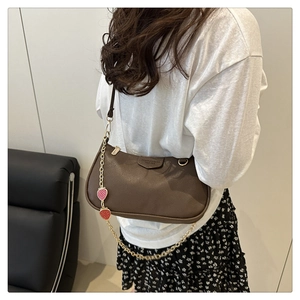 Detail of brown litchi pattern bag with gold chain and strawberry charms decoration