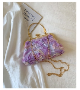 Macro view of purple floral petals on an elegant evening bag with golden metal kiss-lock