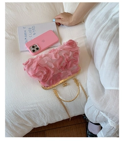 Detail of pink floral shell bag with metal frame, kiss lock and rose petal texture