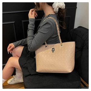 Detail of beige tote bag with skull embossing and rhinestone metal ornament