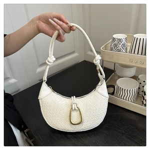 Detail showing white woven crescent bag with knot handle and golden metal ring