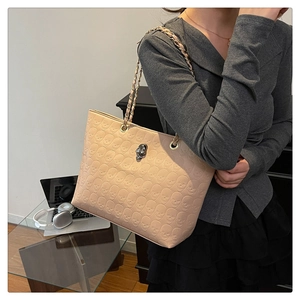 Détail du sac cabas beige avec texture tête de mort en relief et boucle en métal