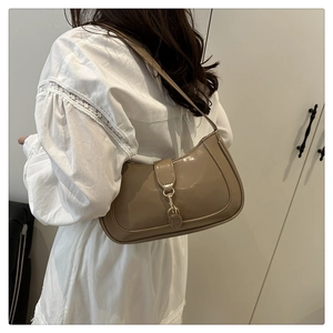 Detail of khaki hobo shoulder bag with glossy finish and gold metal clasp on model