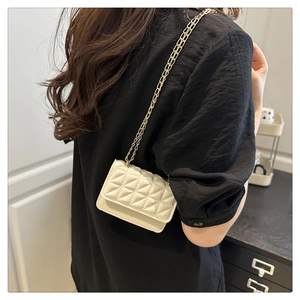 Detailed view of the quilted cream crossbody bag with a gold chain strap on a model