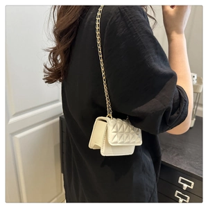 Detail of white quilted handbag with golden chain strap worn by a female model