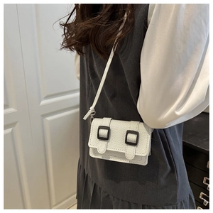 Dettaglio mini borsa a tracolla bianca in pelle grana litchi con fibbie quadrate nere