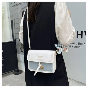 Detail of color-block crossbody bag with woven stitching and decorative silk scarf