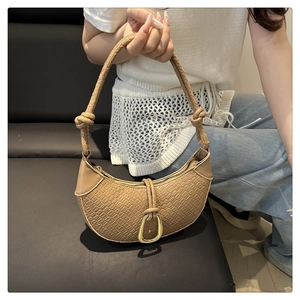 Close-up of woven handle detail and embossed texture on khaki crescent shoulder bag
