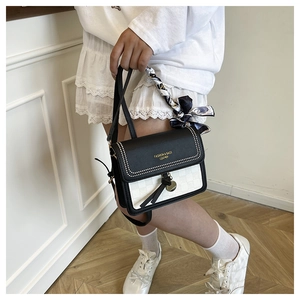 Close-up of contrast square bag with leather rivets and silk scarf wrapped handle
