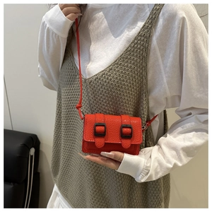 Dettaglio mini borsa a tracolla rosso acceso con pelle testurizzata e doppie fibbie nere