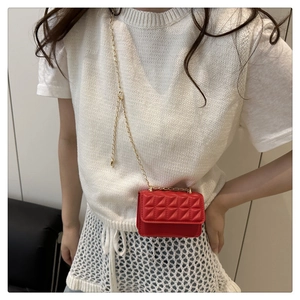 Detail of red quilted mini crossbody bag with gold chain strap on model