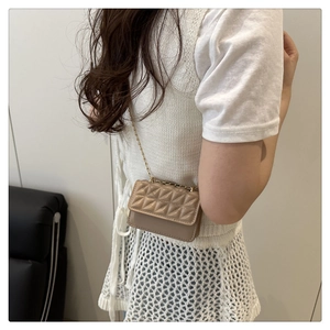 Close-up of khaki quilted mini crossbody bag with gold chain strap on model