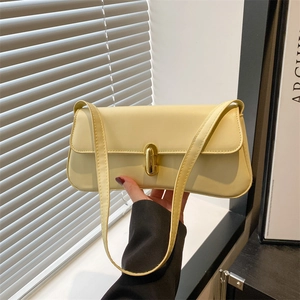 Borsa sottobraccio minimalista in pelle giallo crema con chiusura dorata mostrata a mano