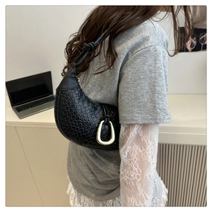 Détail du sac hobo tissé noir avec ferrures dorées et nœud élégant sur la bandoulière