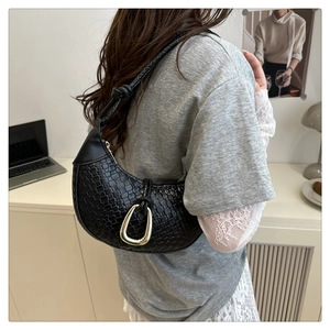 Détail du sac tressé noir en forme de croissant avec boucle dorée et bandoulière