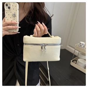 Detail of a beige litchi grain mini handbag with silver zippers and long shoulder strap