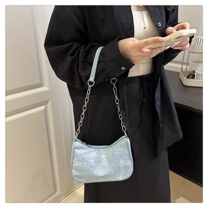 Détail du sac d'épaule bleu clair pailleté avec chaîne argentée sur tenue noire