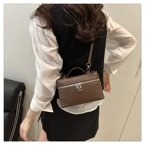 Detail of dark brown pebble leather vanity bag with silver zippers and crossbody strap