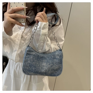 Détail d'un sac en denim bleu clair avec chaîne argentée et finition pailletée