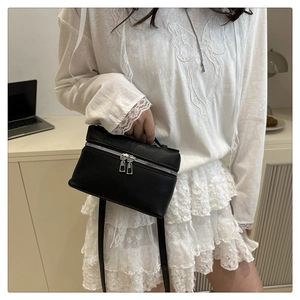 Detail of black pebbled leather vanity bag with silver zippers and handle for women