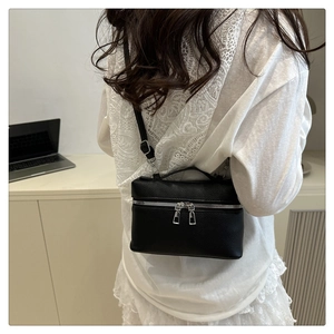 Rear view of a model wearing a black litchi pattern leather crossbody box bag